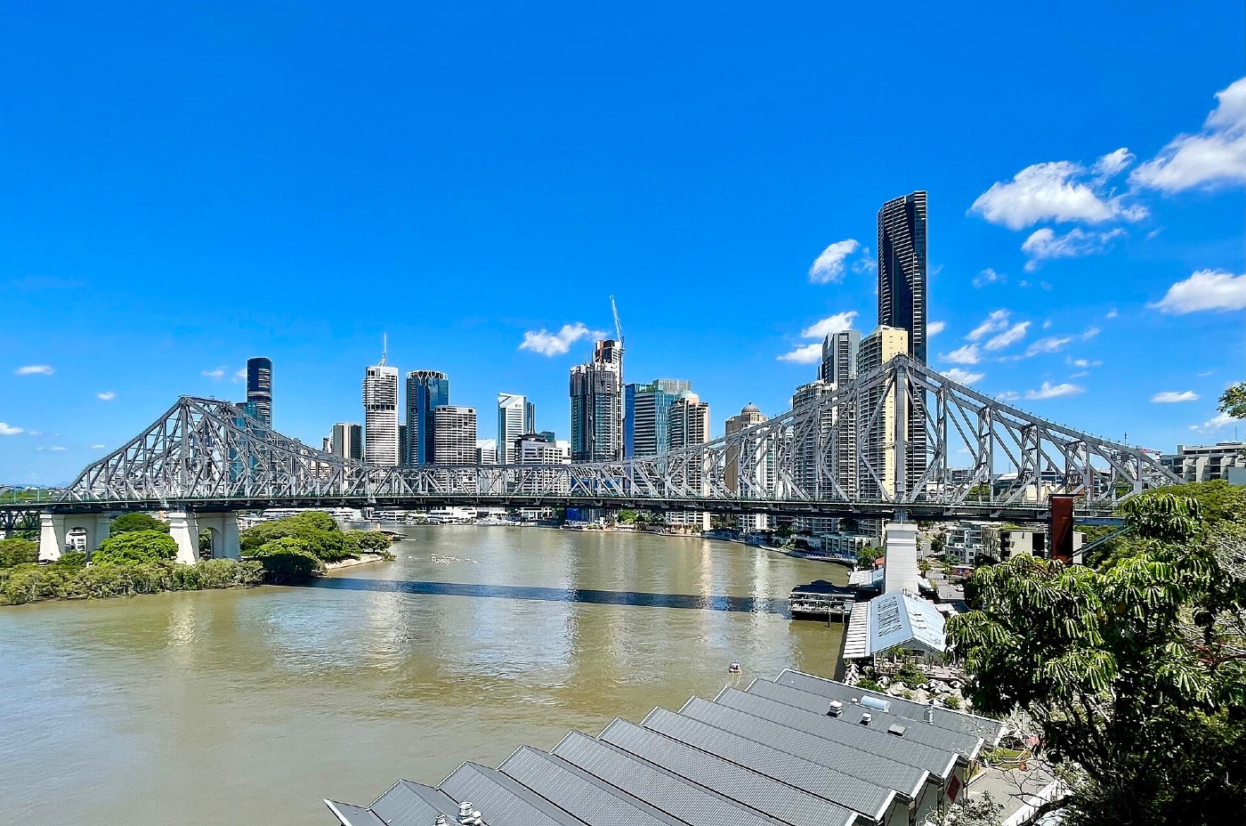 The Story Bridge and Brisbane city skyline over the Brisbane River, under a blue sky