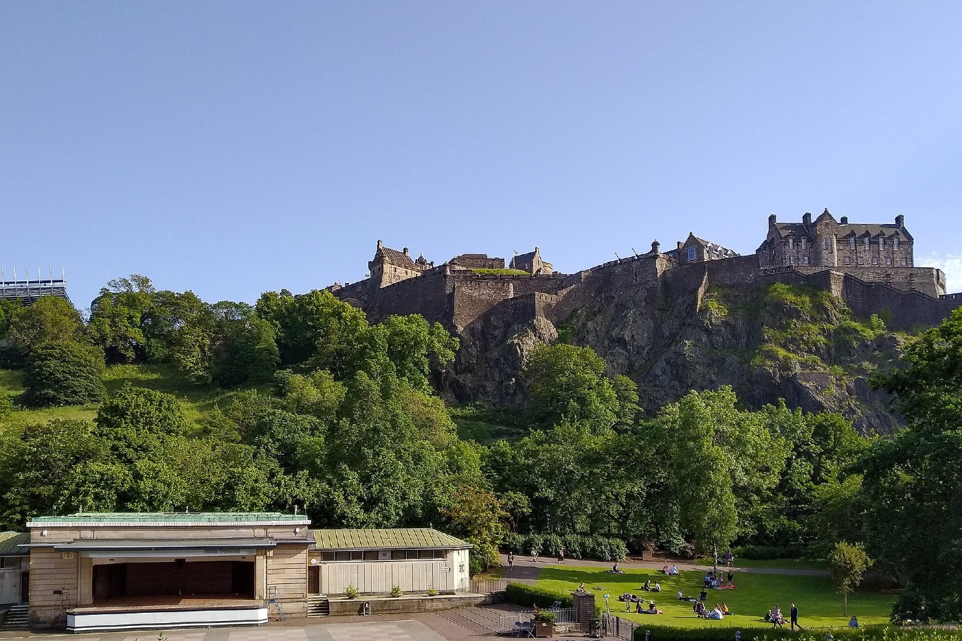 Edinburgh Castle on its rock above green gardens, under a blue sky