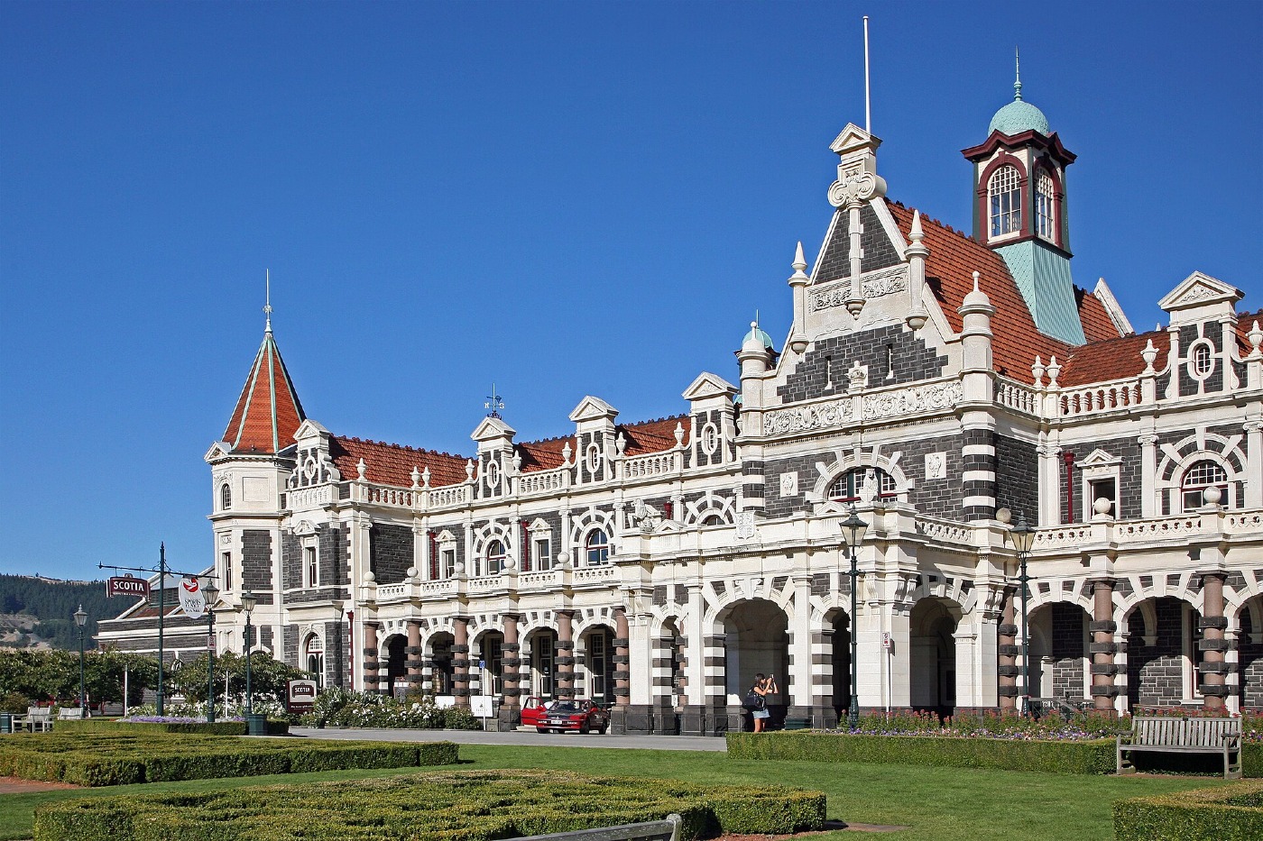 Dunedin Railway Station, an ornate stone building with a clock tower, behind formal gardens