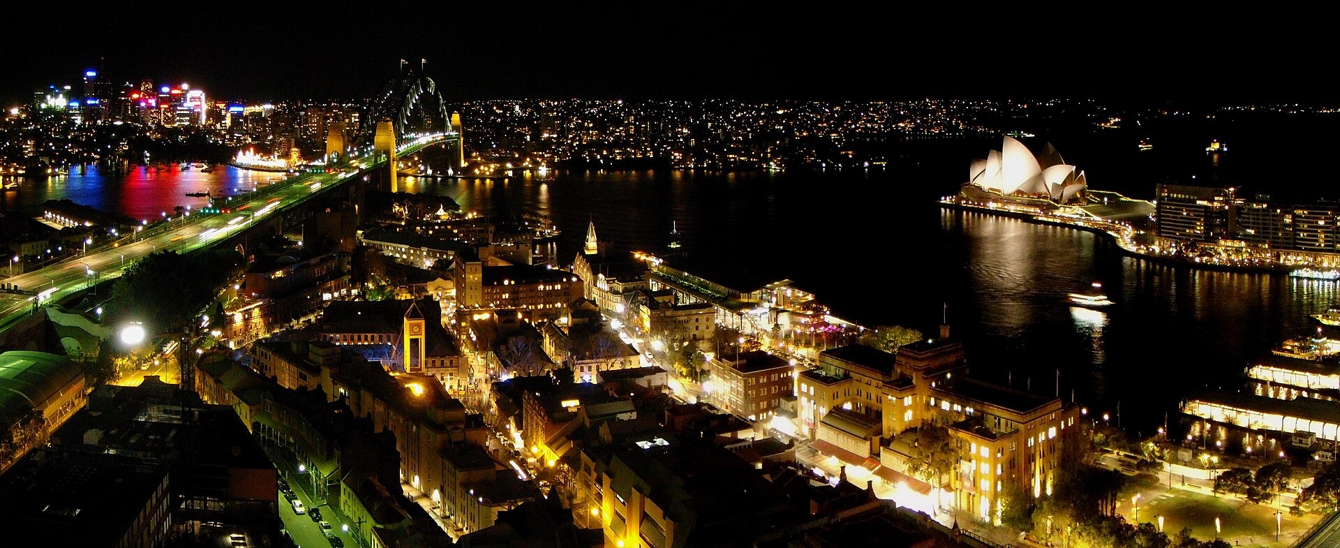 Sydney Opera House and the Harbour Bridge lit up at night above Sydney Harbour